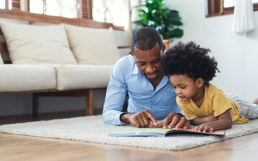 adult and child lying on their tummies reading a book together